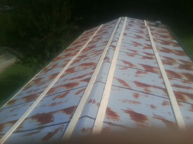 Rusted metal roof panels with new wood purlins before replacement — Storm Damage Roof Repair in Eastlake by Roofing Brothers