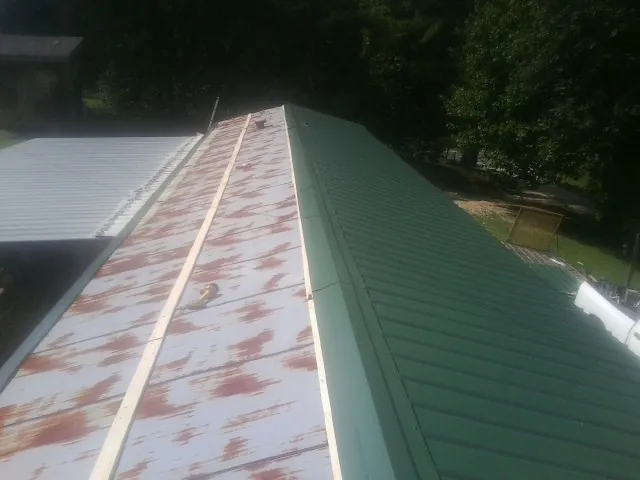 Old rusted panels beside newly installed green metal roofing — Wind Damage Roof Repair by Roofing Brothers in Eastlake