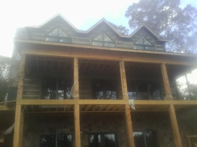 Dormers and porch framing on a large log home under construction — Roof Coating work by our crew in Eastlake