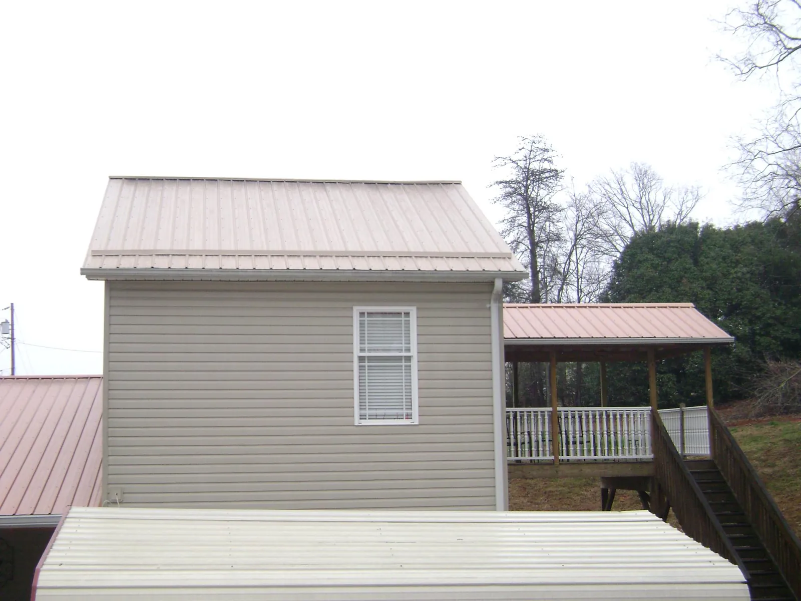 Tan metal roofs on a two story addition and attached porch, from a Roof Replacement job in Eastlake