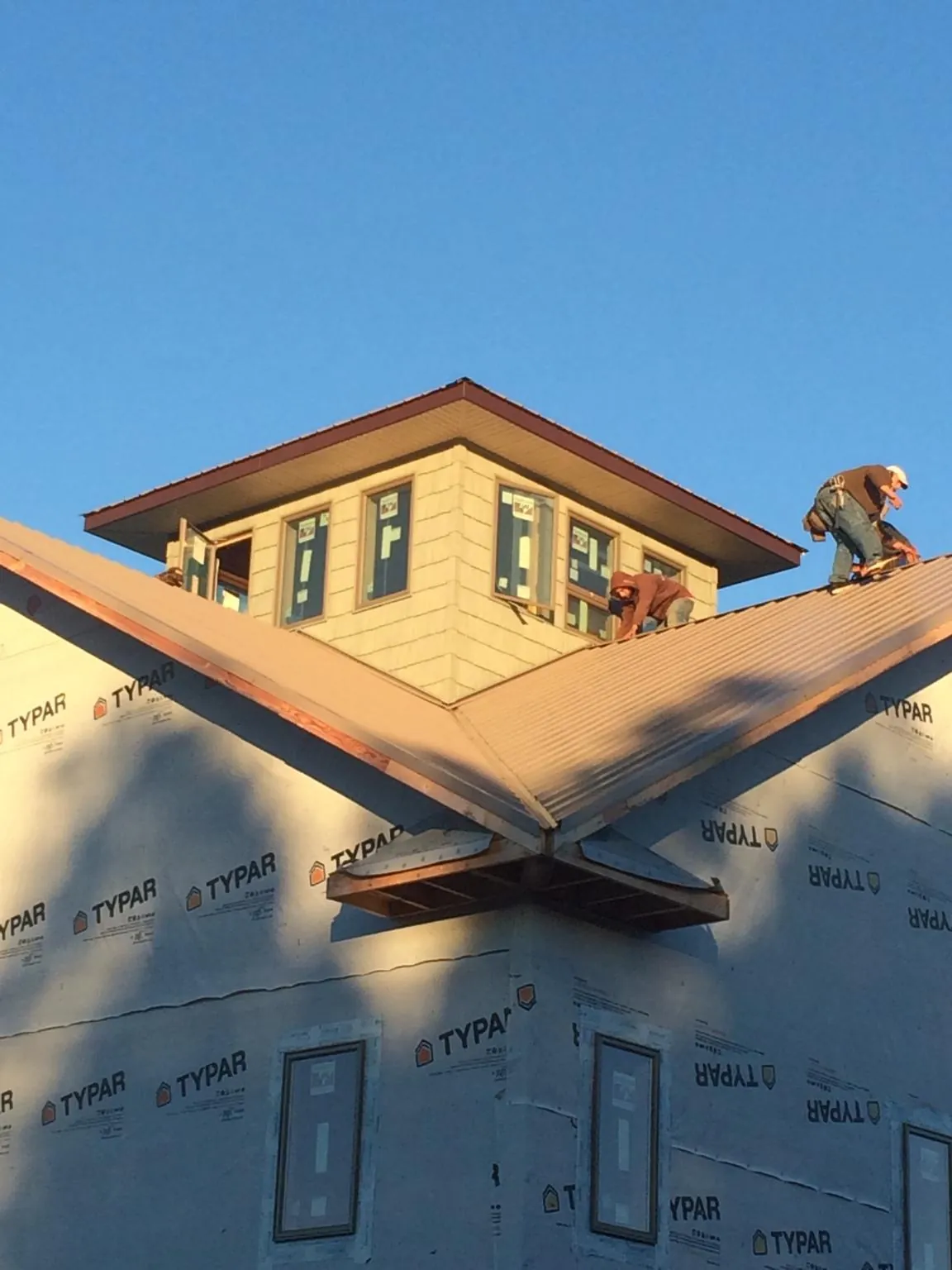 Roofers working around a rooftop cupola on a new metal roof at sunset — Roof Waterproofing in Eastlake by Roofing Brothers